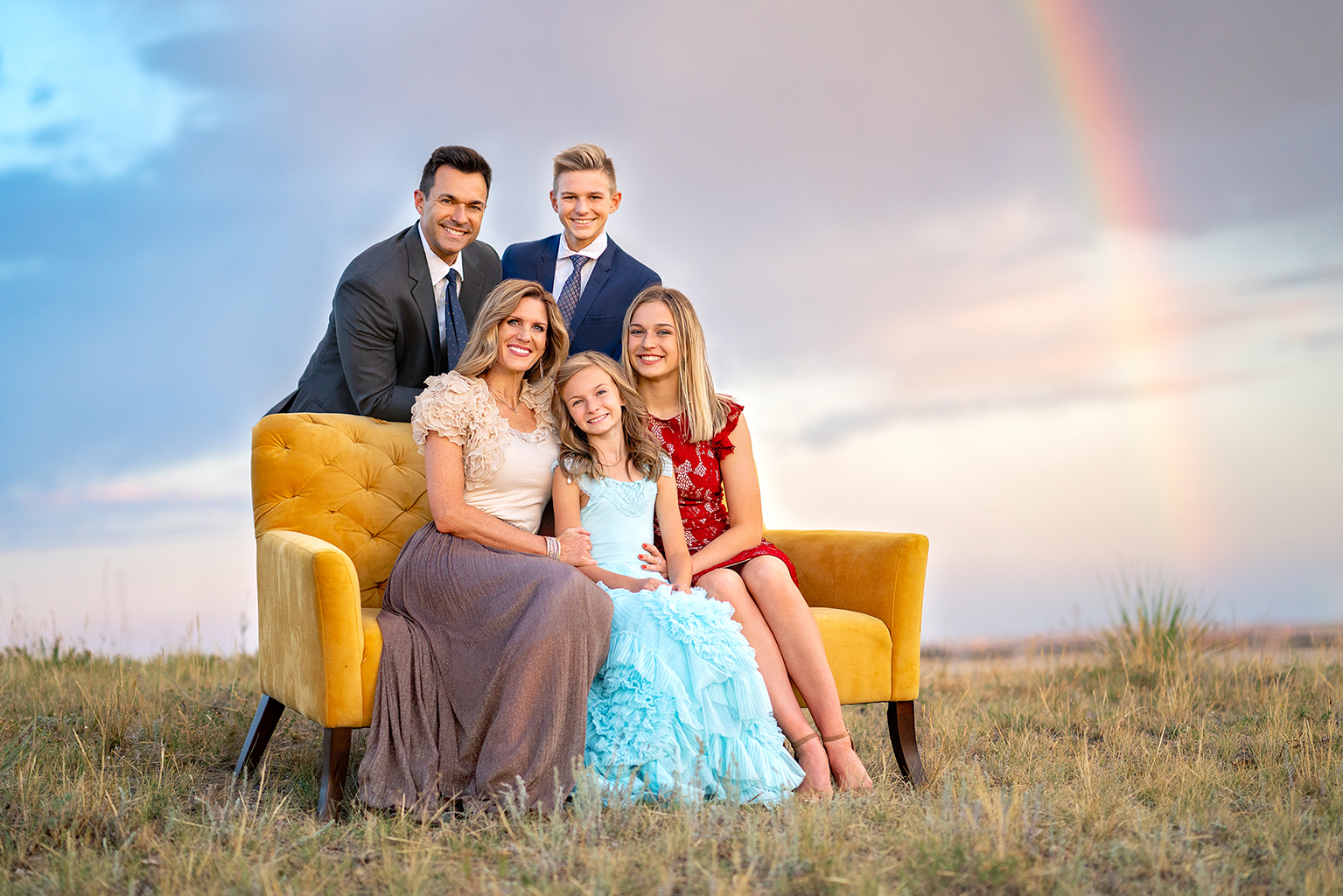 A family of five with a rainbow behind them.