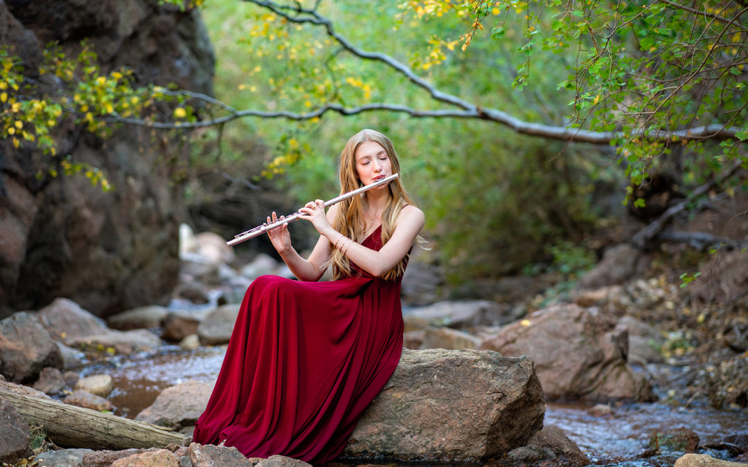 Young lady playing a flute by the stream.