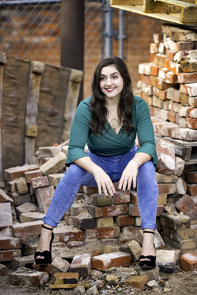 A young women sitting a pile of bricks downtown.