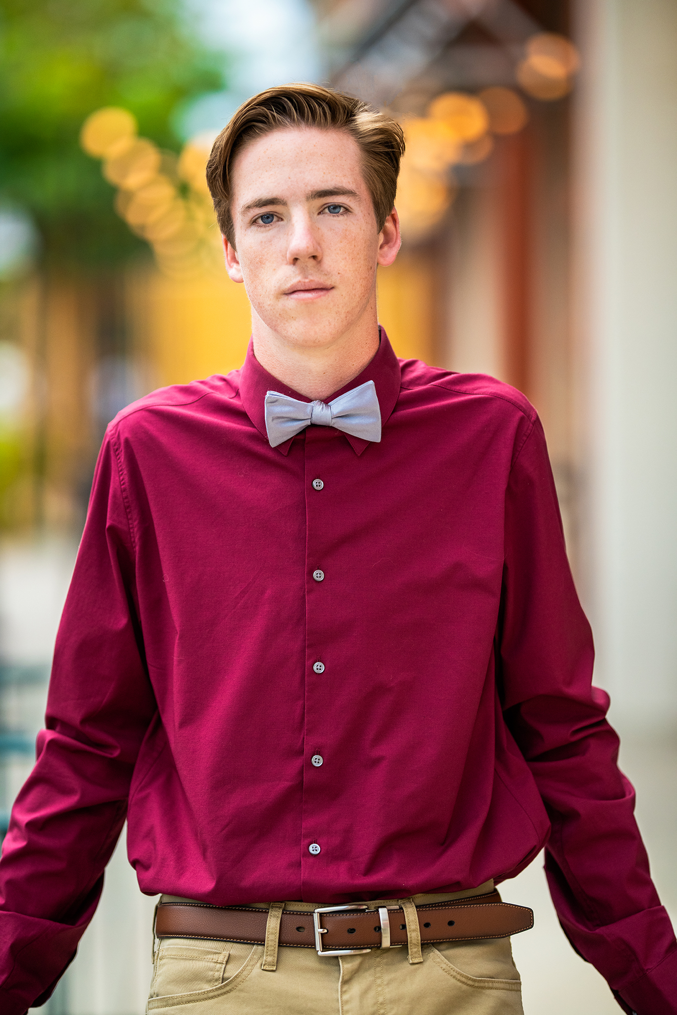 A young man dressed in a maroon shirt with a bowtie.